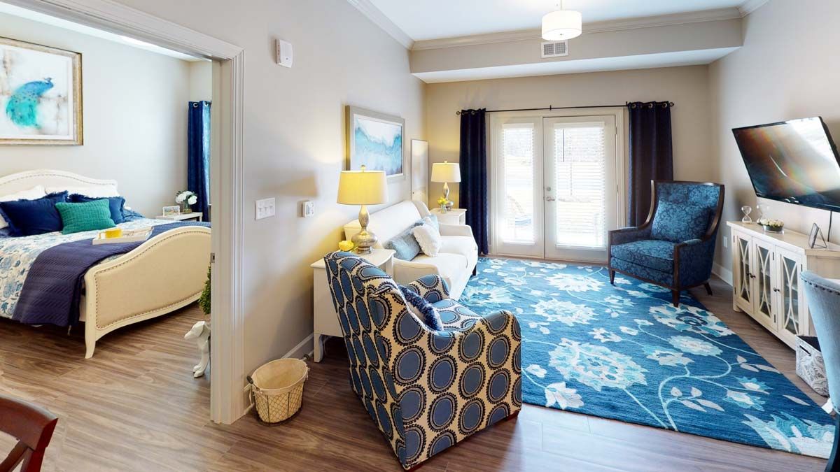 A cozy and bright living room featuring a patterned armchair, a floral rug, and elegant decor.