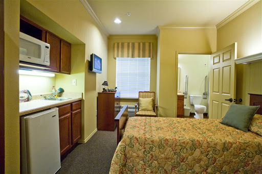 A cozy hotel room featuring a kitchenette, comfortable seating, and an adjoining bathroom.