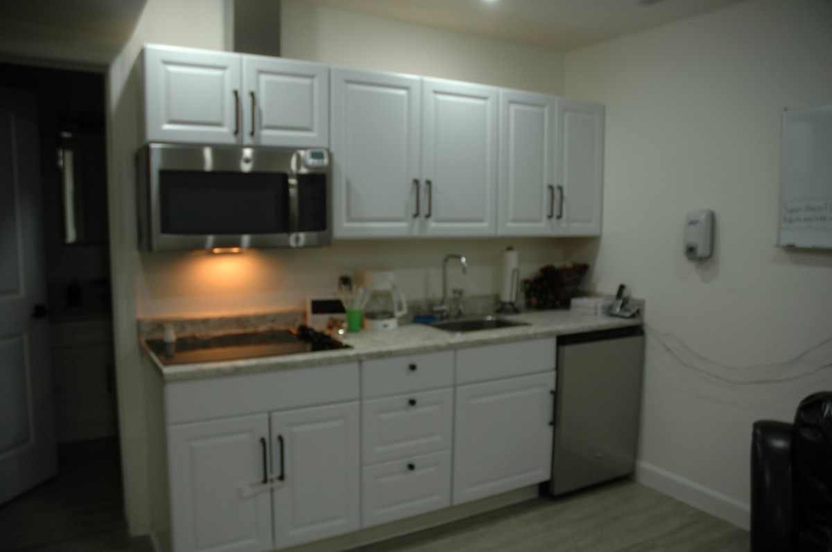 A modern kitchen setup featuring white cabinets, a microwave, and a small refrigerator.