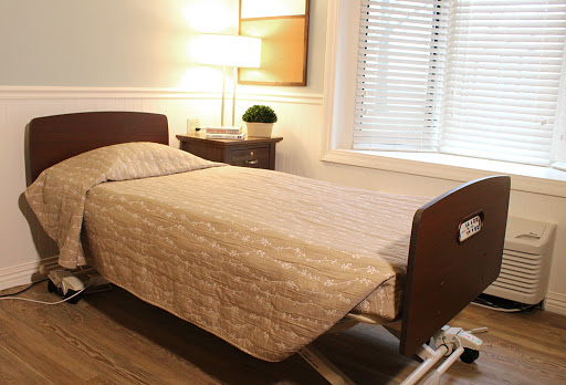 A cozy bedroom featuring a neatly made bed, a bedside lamp, and natural light filtering through the window.