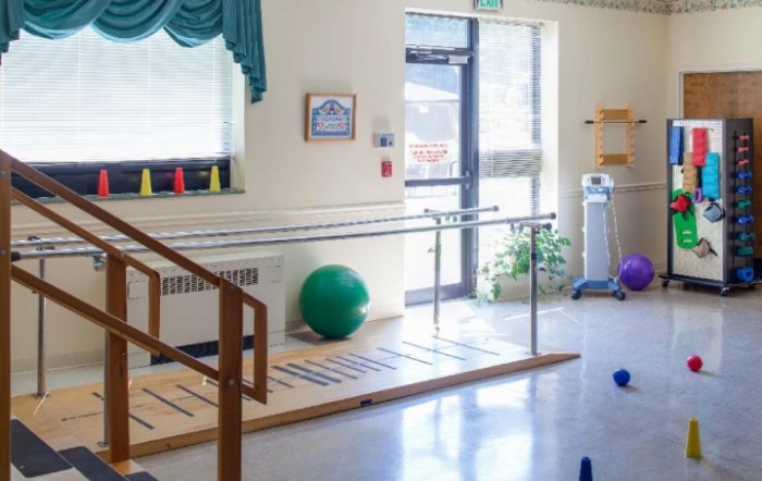 A rehabilitation room equipped with parallel bars and exercise equipment for physical therapy sessions.