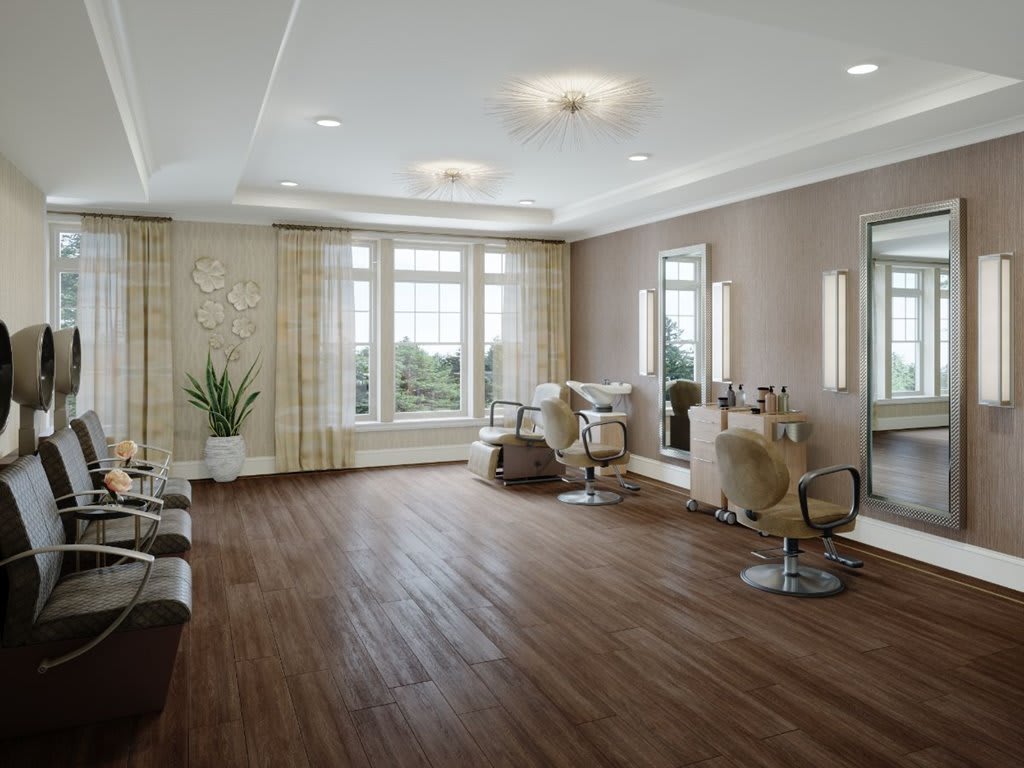 A modern salon interior with sleek wooden flooring and ample natural light, featuring stylish chairs and large mirrors.
