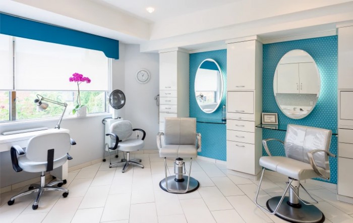 A modern and stylish hair salon interior with bright lighting, comfortable chairs, and large mirrors.