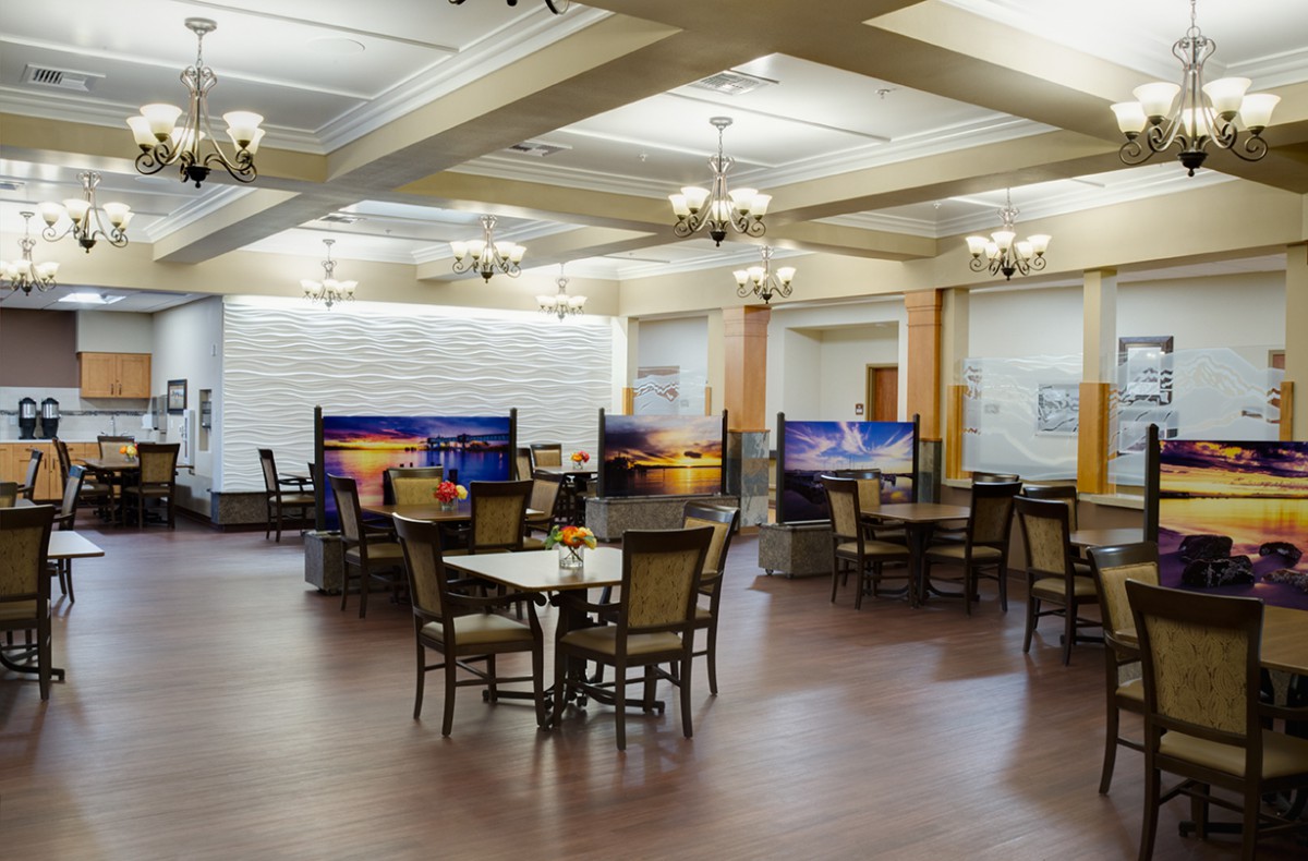 A spacious dining area with elegant chandeliers and partitioned tables.