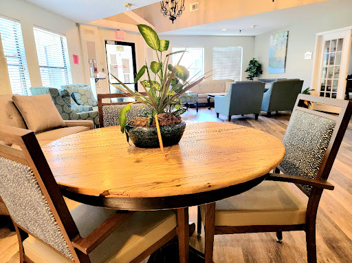 A cozy dining area featuring a wooden table with a houseplant centerpiece and comfortable chairs.