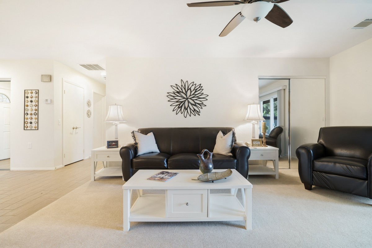 A modern living room featuring a black sofa, white coffee table, and elegant decor.