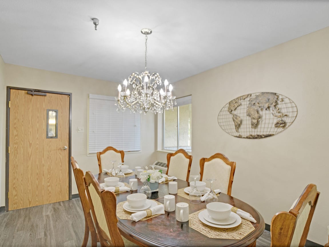 A well-decorated dining room with a chandelier and an elegantly set table.
