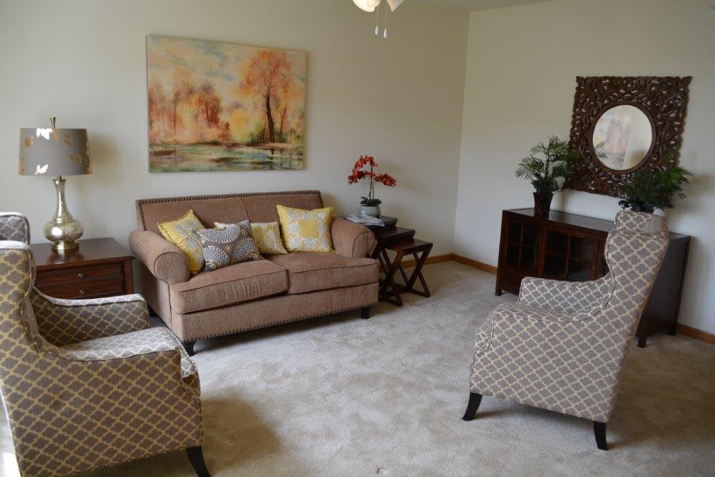 A cozy living room with a sofa, armchairs, and wall art.