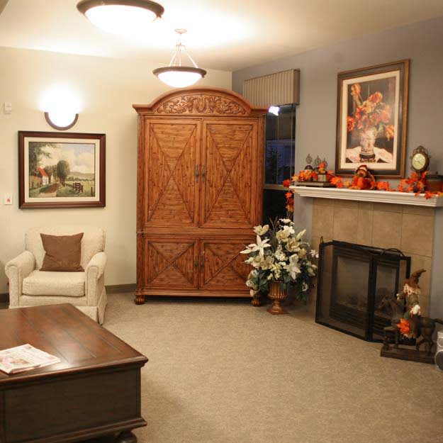 A cozy living room with a large wooden armoire, decorated fireplace, and comfortable seating.