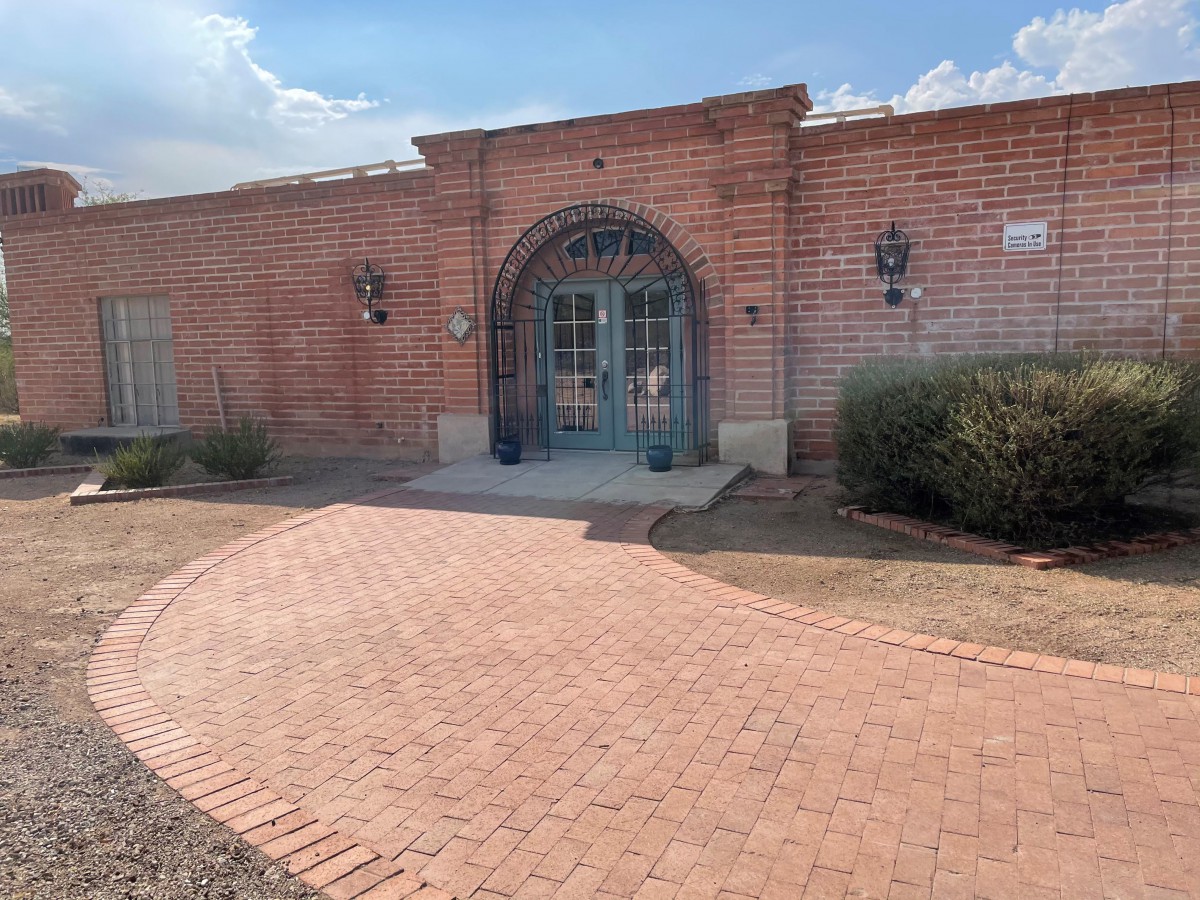 A brick building with an arched entrance and a paved pathway leading to it.