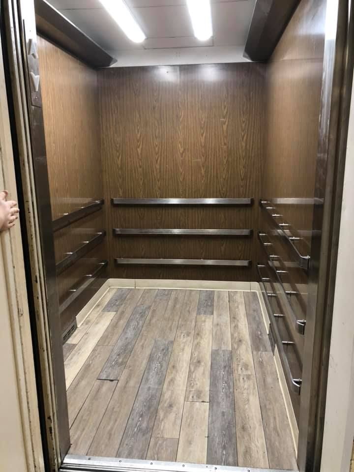 The interior of a modern elevator with wood paneling and stylish flooring.