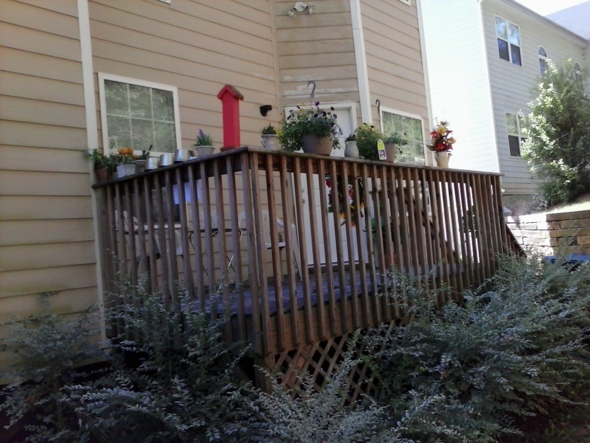 A wooden deck with plants in pots attached to the side of a house.