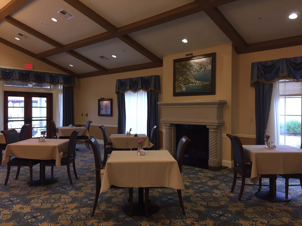 A cozy dining room with elegantly set tables and a fireplace.