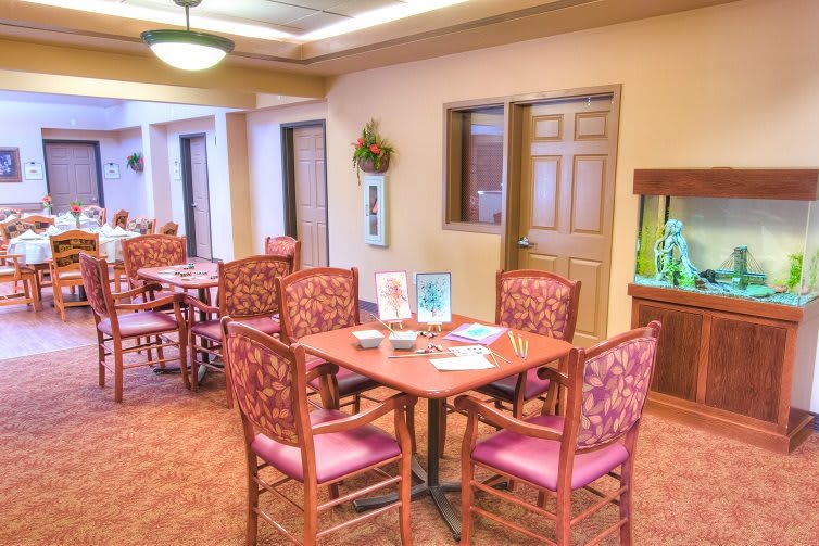 A cozy dining area with tables and chairs, featuring a decorated wall and ceiling lighting.