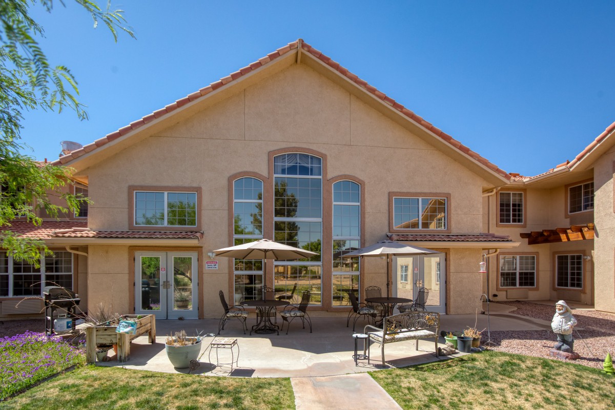 A spacious house with a large patio and outdoor seating area in the backyard on a sunny day.