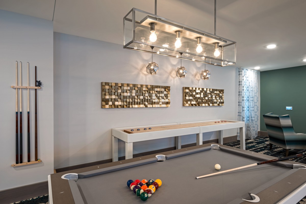 A stylish billiard room with a modern pool table, contemporary lighting fixtures, and decorative artwork on the walls.