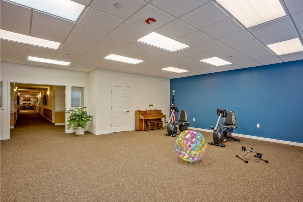 A spacious indoor room with gym equipment and bright overhead lighting.