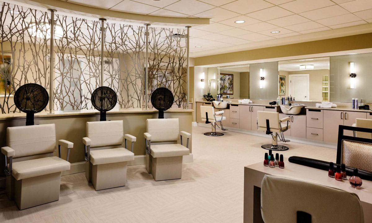 A modern and spacious beauty salon with comfortable chairs and hair drying stations.