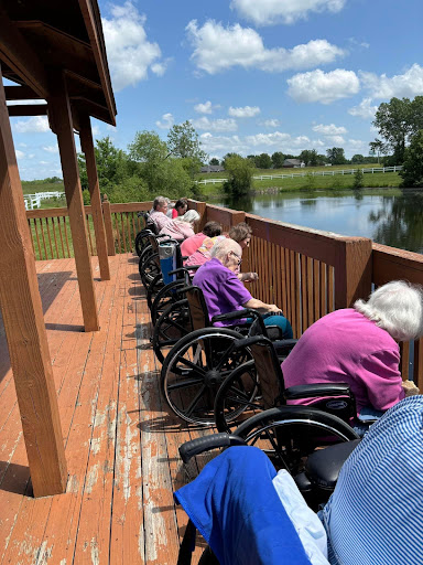 Elderly residents enjoying the serene view by the lake on a sunny day.