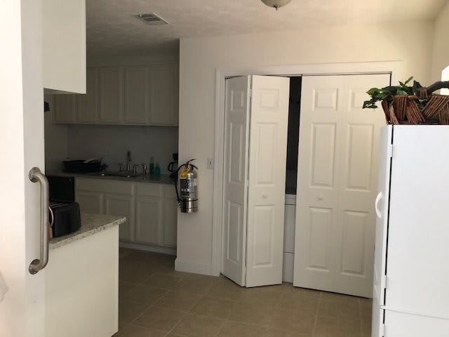 A clean kitchen interior with white cabinets and a partially open doorway.