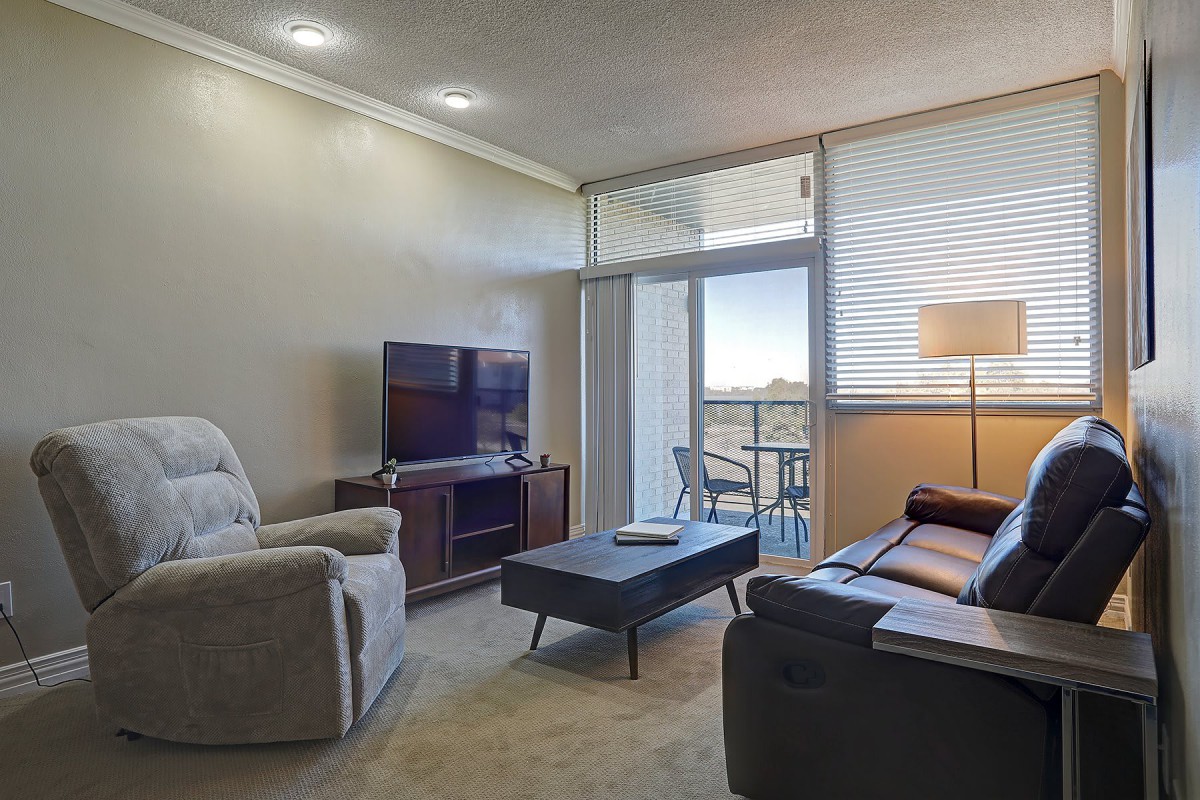 A cozy living room with modern furniture and a view of the balcony.