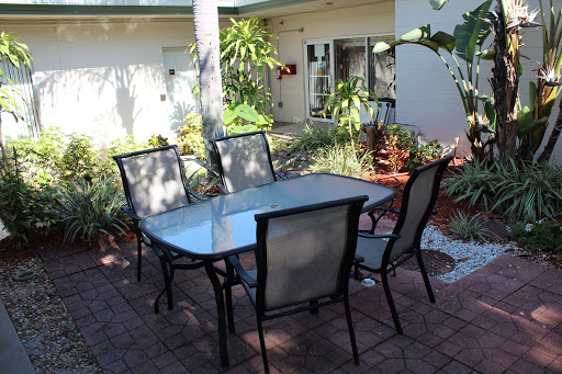 A cozy outdoor dining area with a glass table and chairs surrounded by greenery.