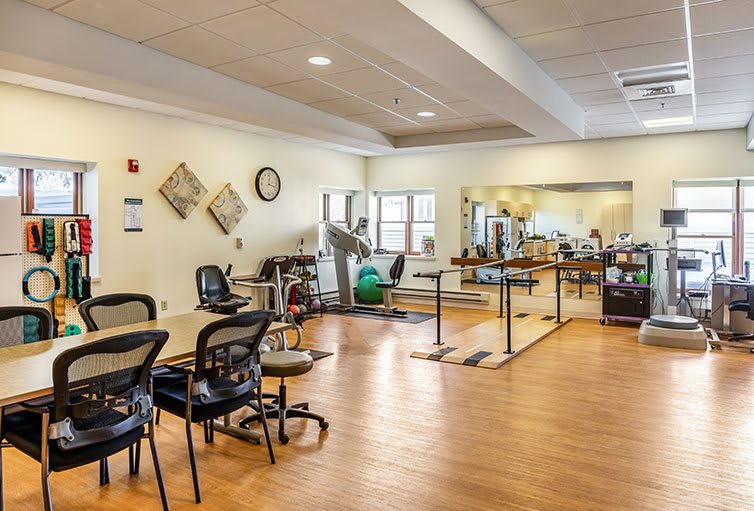 A well-equipped rehabilitation center therapy room with exercise equipment and seating area.