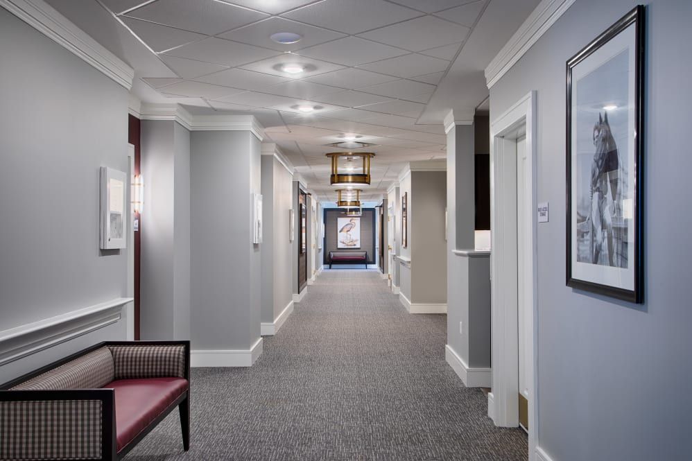 A well-lit hallway with carpet flooring and multiple doors on either side.