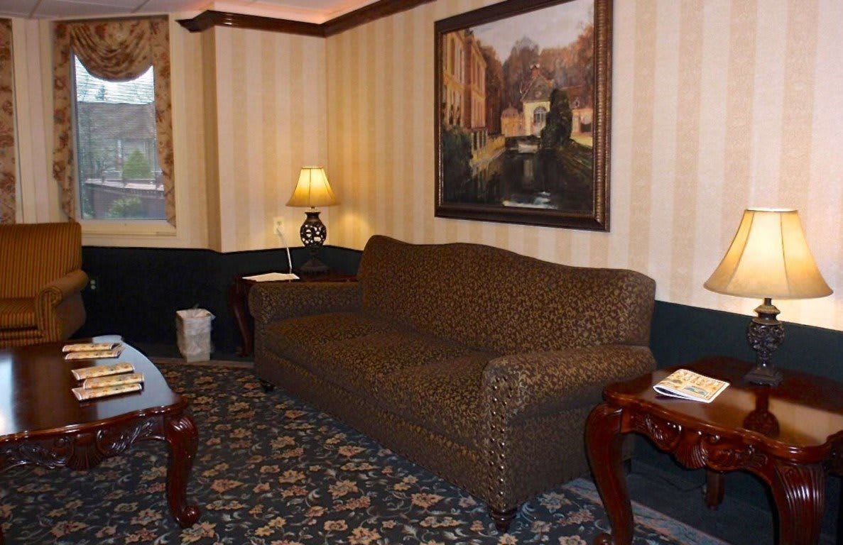A cozy living room with a patterned sofa, side tables, a lamp, and a decorative painting on the wall.