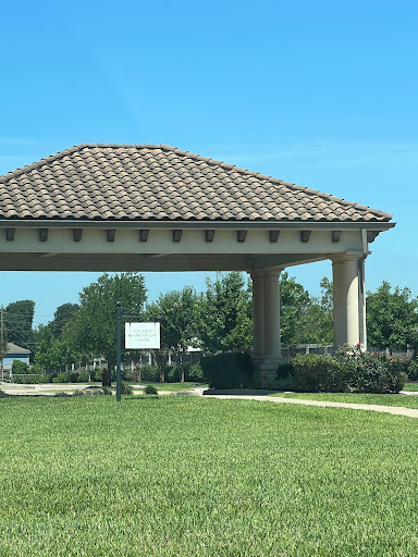 A pavilion with a tiled roof surrounded by greenery on a clear day.
