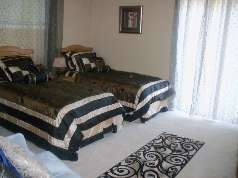 A cozy bedroom with two neatly made single beds, featuring black and white striped bedding and a patterned carpet.