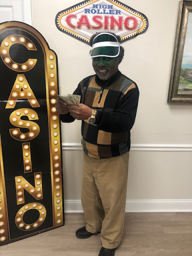 A man dressed in casual attire holding cash next to a brightly lit casino sign.