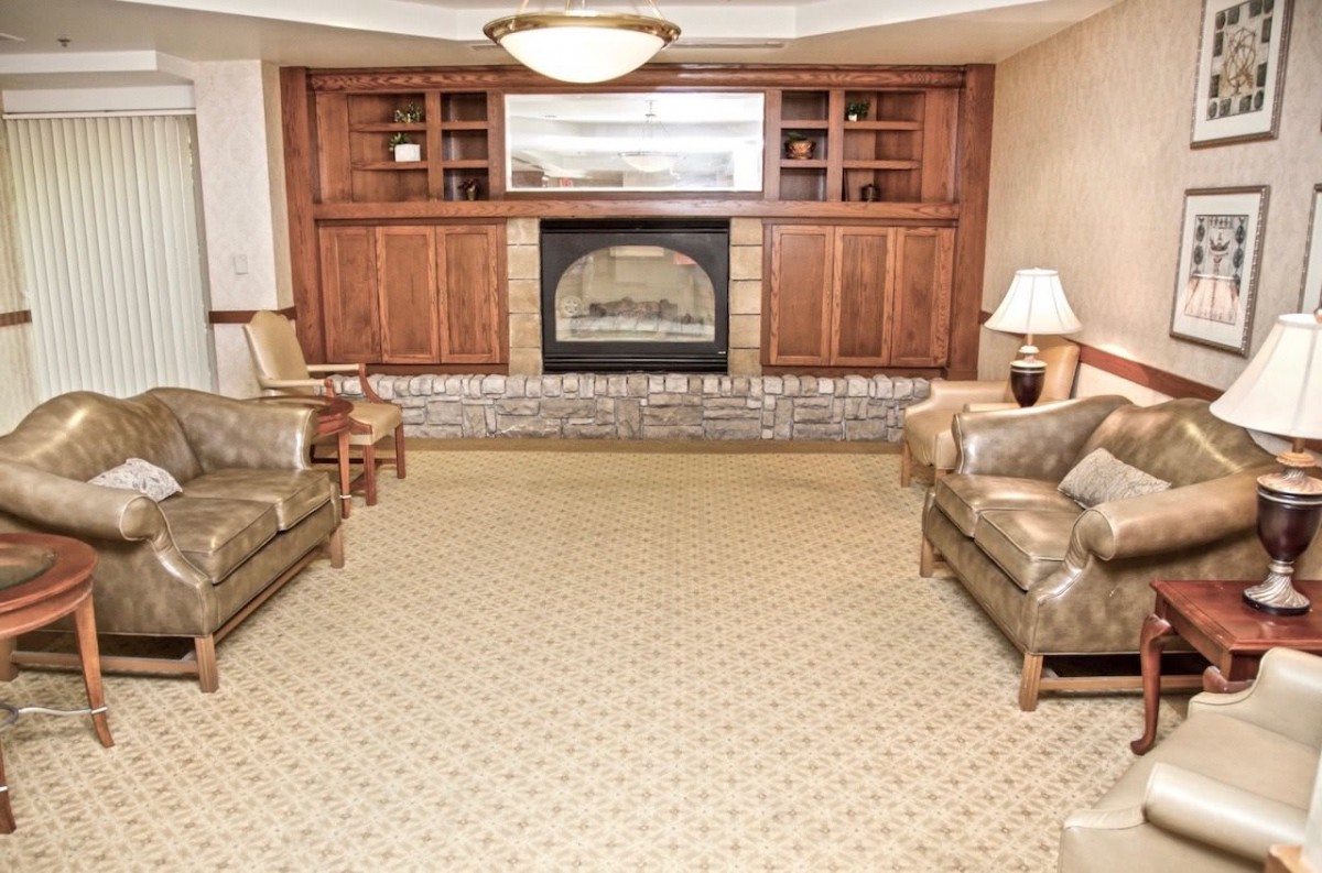 A cozy living room with a fireplace, sofas, and wood paneling.