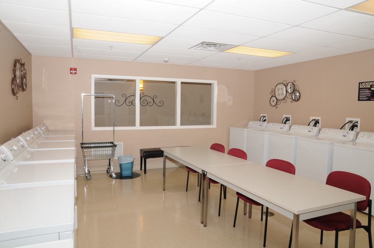 A clean and organized laundry room with tables and chairs.