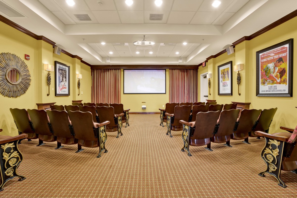 An empty auditorium with rows of seats facing a large screen.