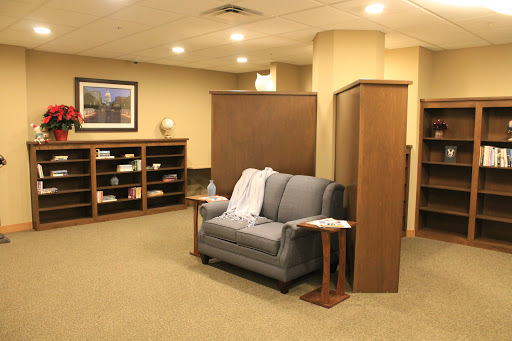 A cozy lounge area featuring a gray sofa and wooden shelves, perfect for relaxation.
