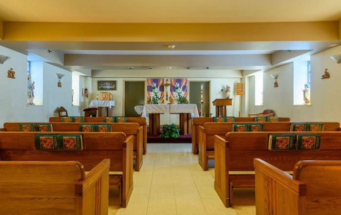 Interior view of a small church with wooden pews and an altar.