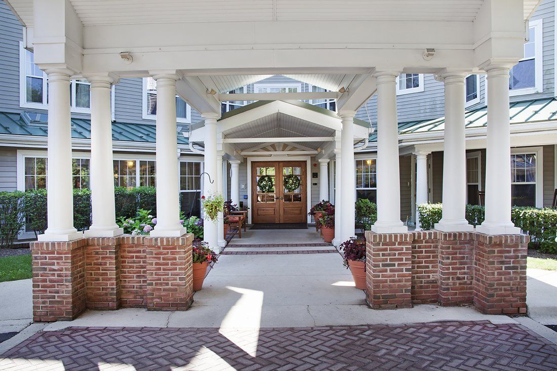 A welcoming entrance to a building with white columns and brick accents.