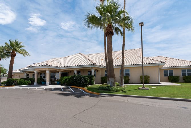 A suburban building with palm trees under a partly cloudy sky.