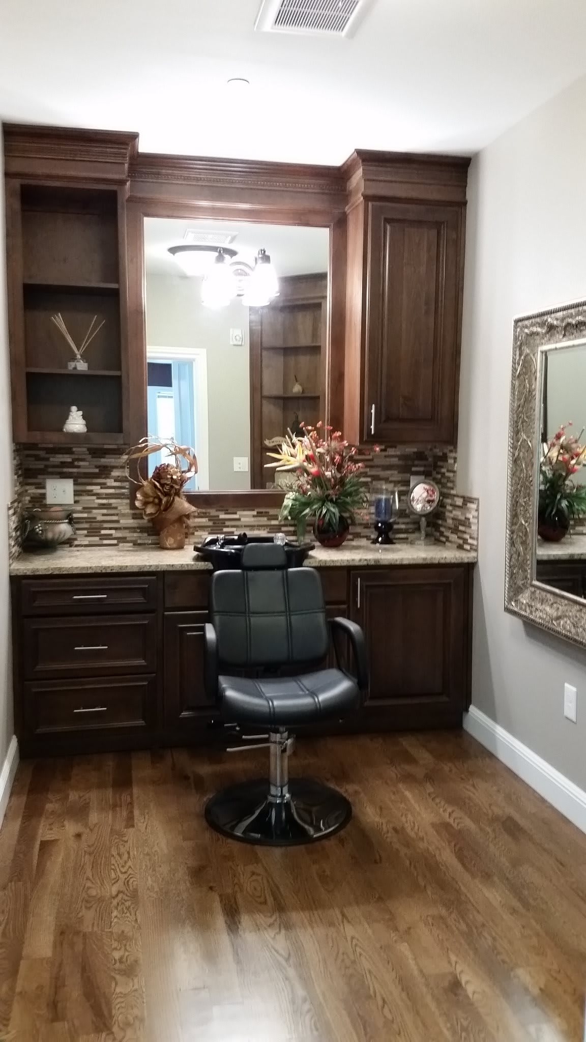 A well-equipped salon space featuring a barber chair, elegant cabinetry, and decorative elements.
