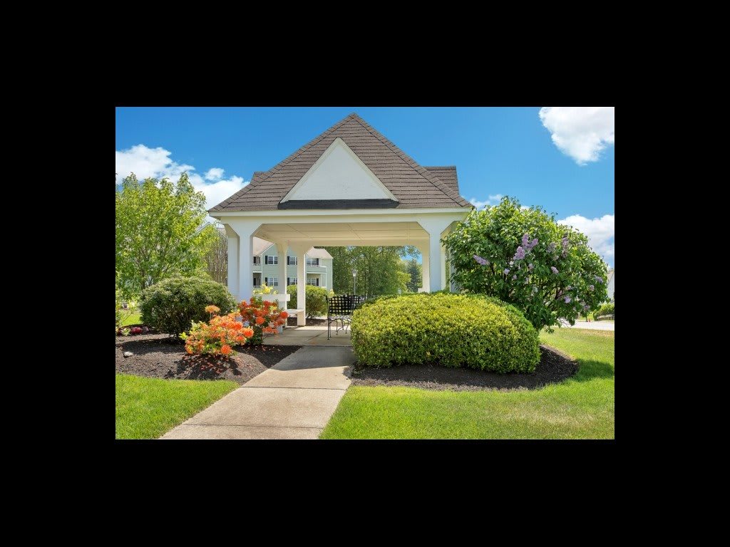 A charming gazebo surrounded by lush greenery and a well-maintained garden path.