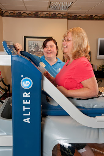 A healthcare professional assists a patient during a rehabilitation exercise using specialized equipment.
