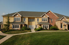 A suburban residential building with a well-maintained lawn under a clear blue sky.