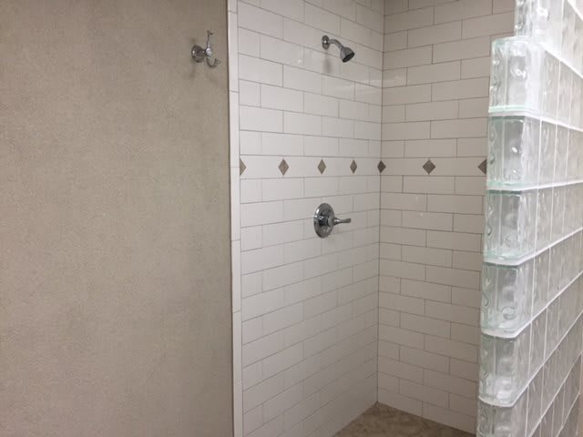 A modern shower with white tiled walls and a central showerhead.