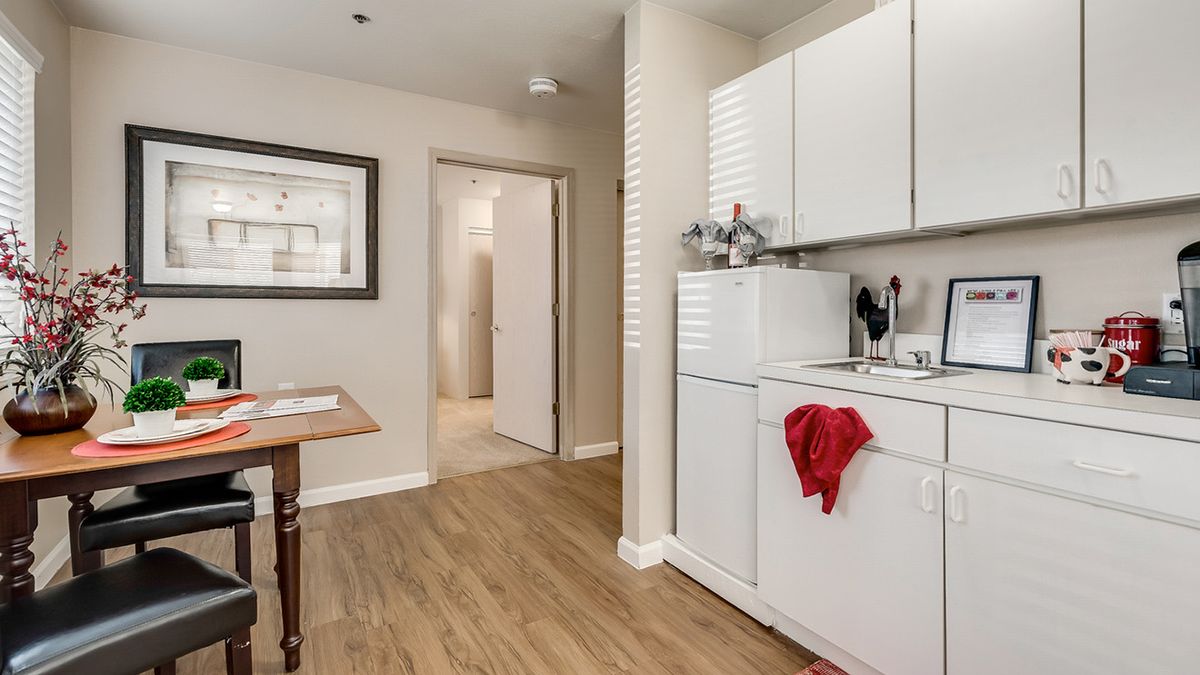 A cozy laundry area with a washing machine, dryer, and white cabinetry on a wooden floor.