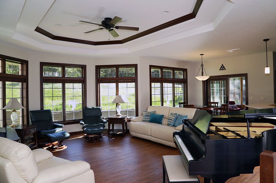 Spacious living room with large windows, comfortable seating, and a piano.