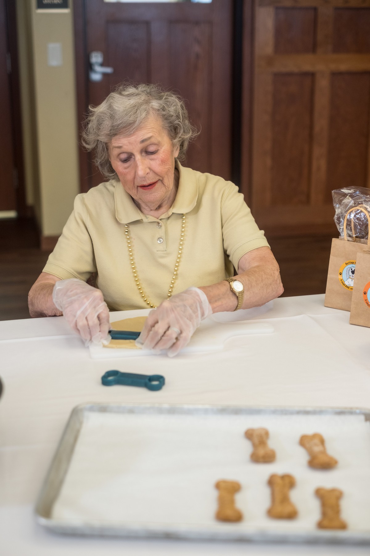 An elderly woman crafting homemade dog treats in the kitchen.
