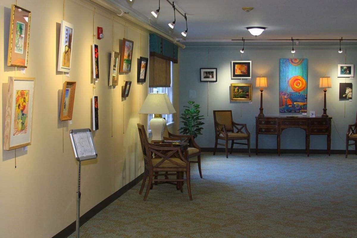 Interior view of an art gallery with paintings displayed on the walls and cozy seating arrangements.