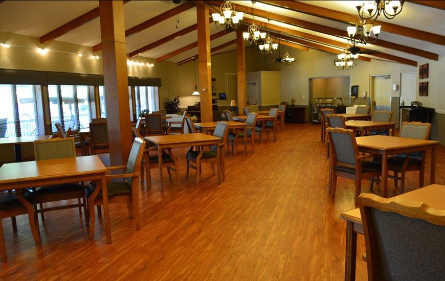 A cozy dining area with wooden flooring, tables, and chandeliers.