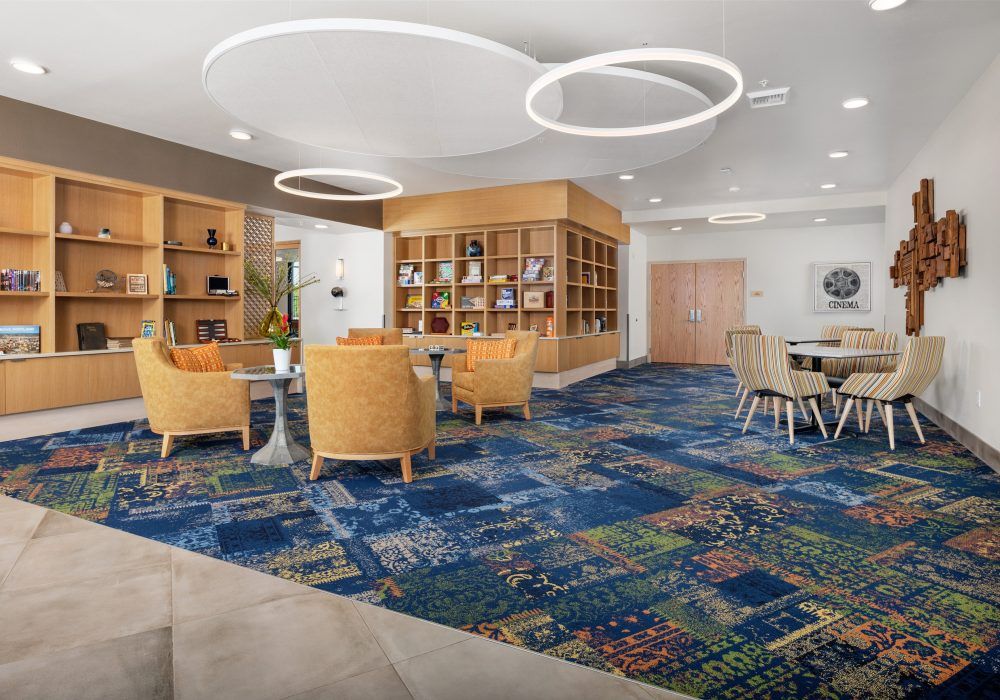 A modern lounge area featuring comfortable seating, bookshelves, and unique ceiling lights.